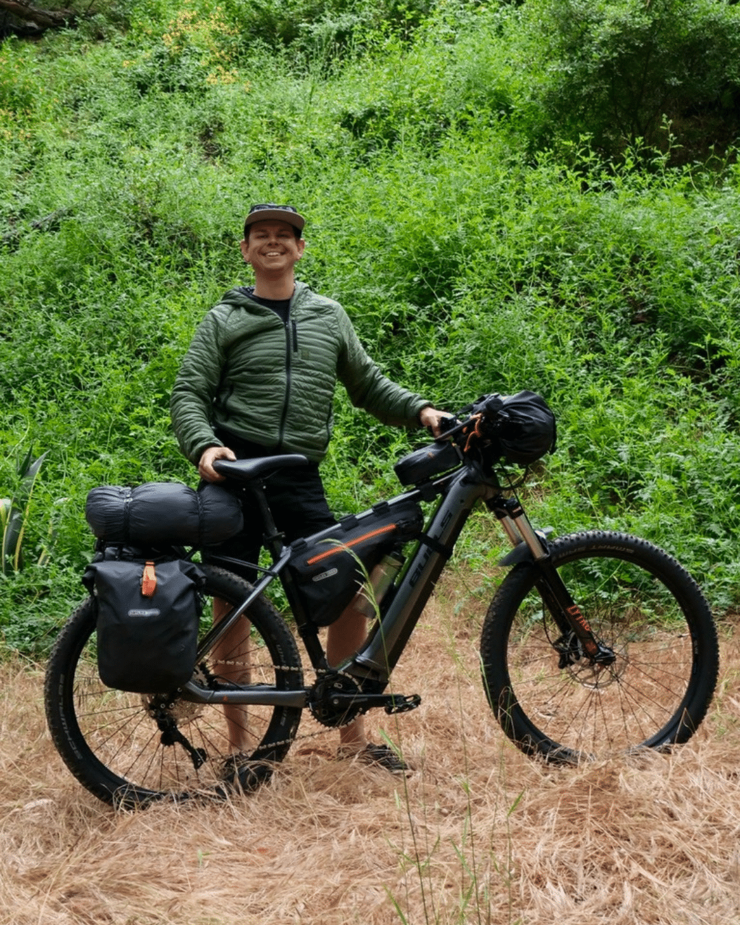 An outdoorsy man smiling at camera with a Bulls ebike ready for an adventure.